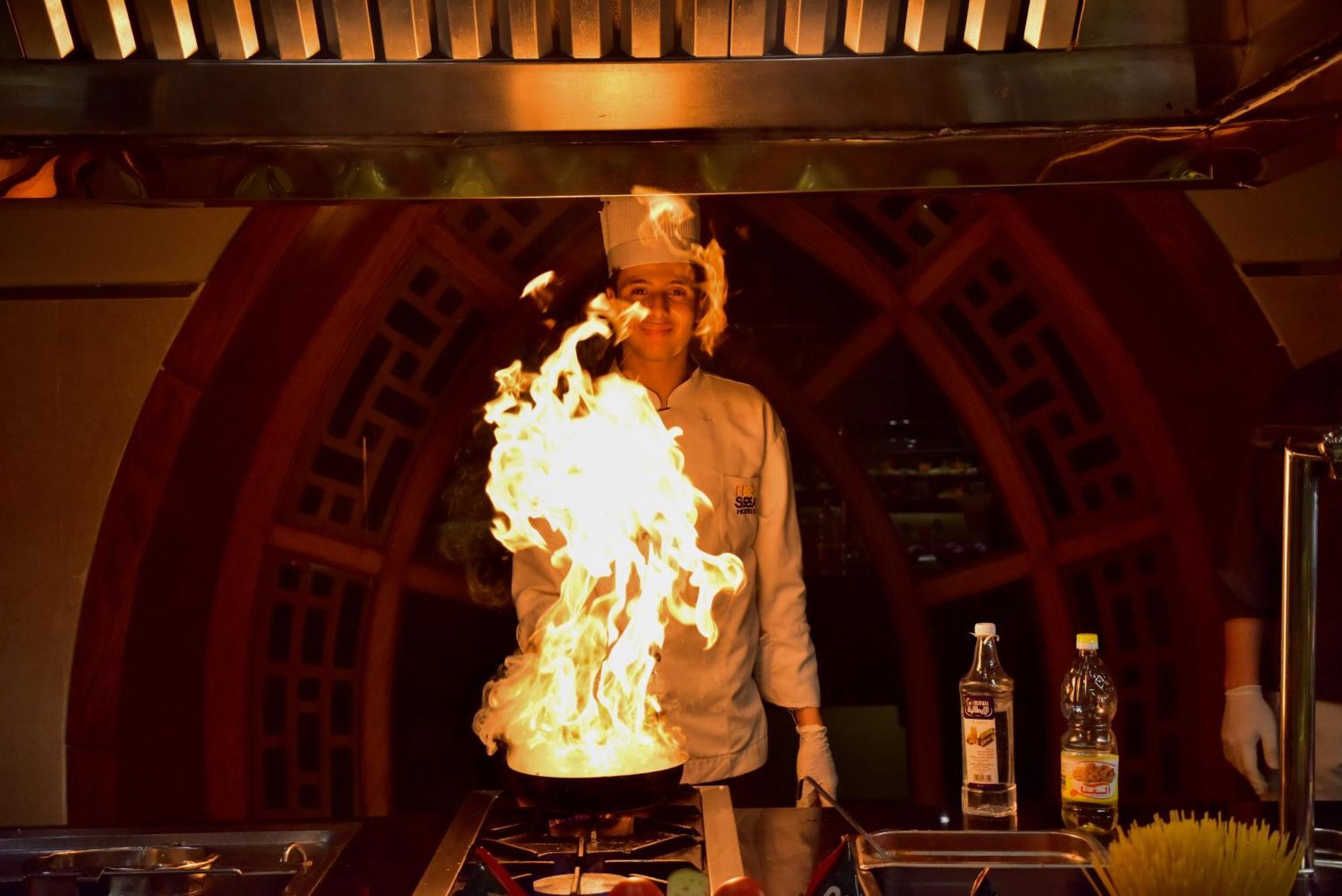 The Grand Hotel Sharm El Sheikh Bagian luar foto A chef cooking with a flaming wok